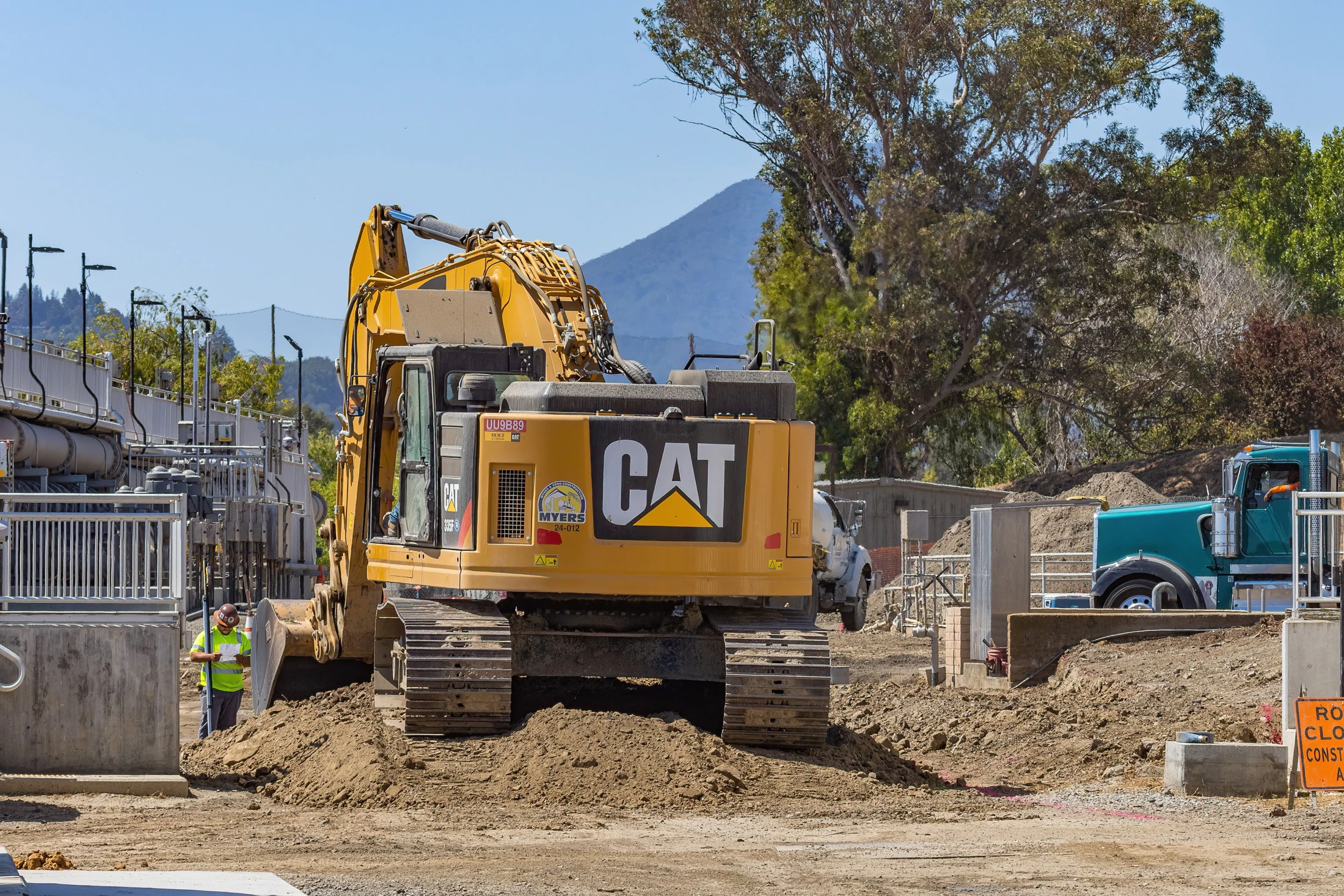 Excavator, truck and site worker during construction
